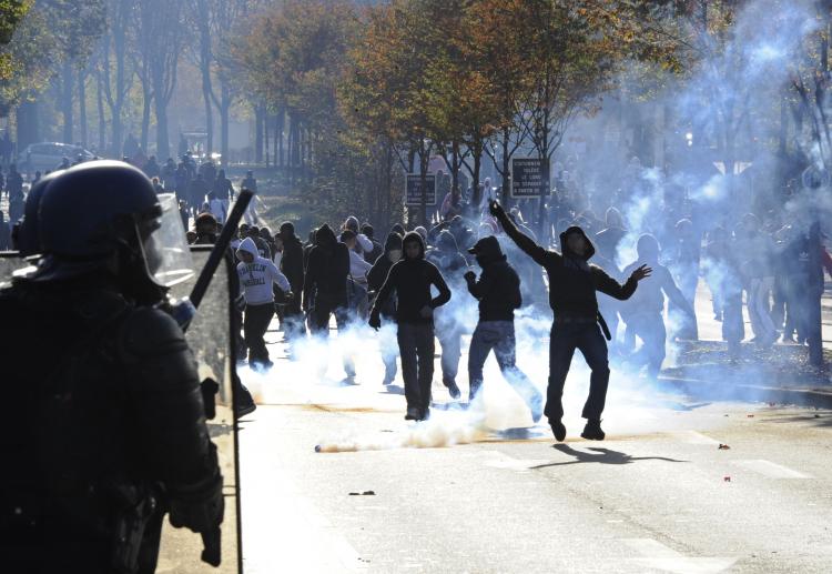 Youth throw stones to anti-riot policemen on October 20 in Nanterre, a western Paris suburb, during protests against pensions reform. Strikes threaten to paralyze France's economy after a million people took to the streets. (BERTRAND GUAY/AFP/Getty Images)