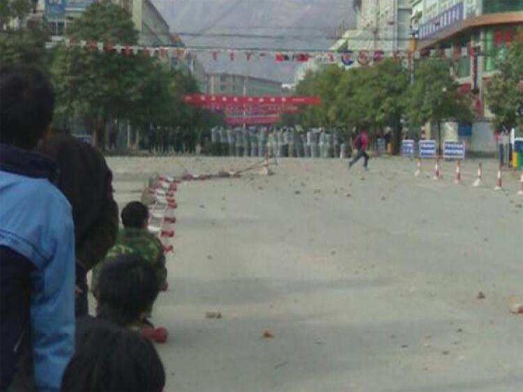 People watch armed police from the side of the street. Thousands of people rioted in Gansu province protesting the regime's move of an office, resulting in a termination of reconstruction of houses affected by the Sichuan earthquake. (The Epoch Times)