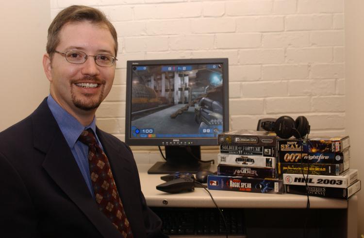 NEW RESEARCH: Dr. Douglas Gentile sits near a computer screen and a stack of video games. As the director of research for the National Institute on Media and the Family, Gentile has conducted several research projects on video games, including their addic (Dave Gieseke/Iowa State University)