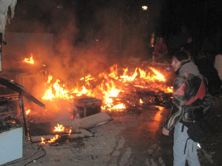 Passerby watches fire burning from rioting by youths in Athens. (Neli Magdalini Sfigopoulou/The Epoch Times)