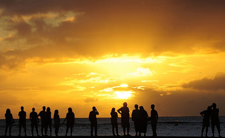 People gather to watch the sunset from Waikiki Beach in Honolulu, Hawaii