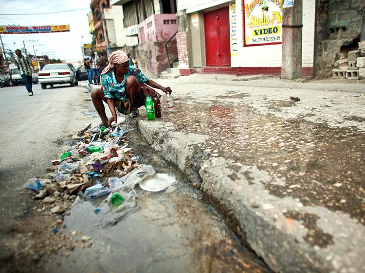 STRUGGLE FOR WATER: A woman collects water from a broken pipe in the street of Haiti's capital Port-au-Prince on Jan. 19. (Uriel Sinai/Getty Images)