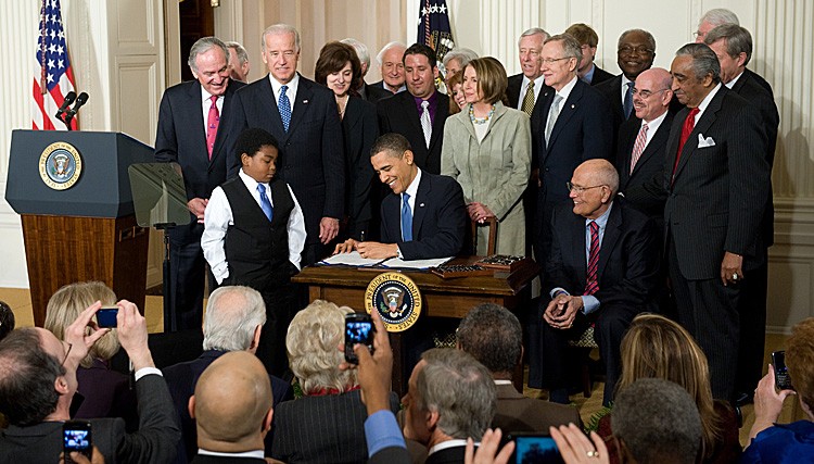 President Barack Obama, surrounded by Democratic lawmakers, signs the health care insurance reform legislation during a ceremony in the East Room of the White House, March 23, 2010. The Department of Justice will not appeal a ruling by Atlanta's 11th Circuit Court that the mandatory insurance requirement is unconstitutional. (SAUL LOEB/AFP/Getty Images)