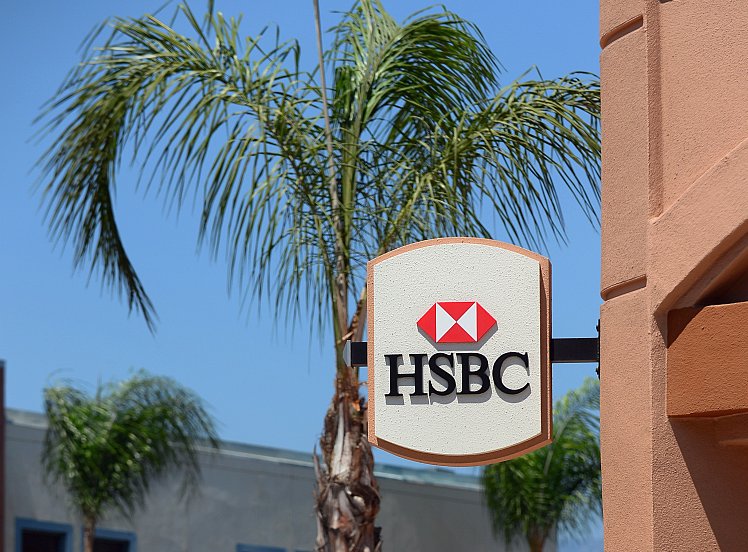 A cyclist rides past a branch of HSBC