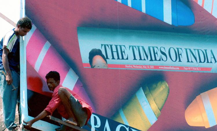 Indian workers puting up a billboard advertising a newspaper on 19 May 2005 in Mumbai. (Indranil Mukherjee/AFP/Getty Images)