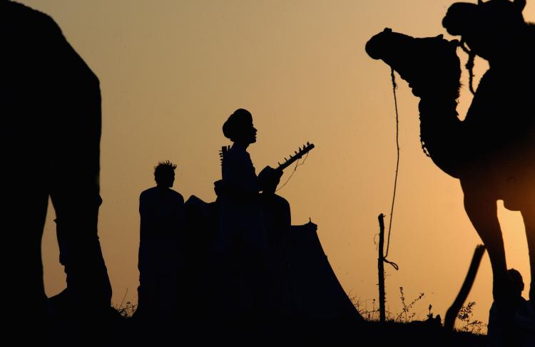 Camel riders play music as the sun falls in Pushkar, India, outside a massive market which attracts traders and tourists alike. (Ami Vitale/Getty Images)