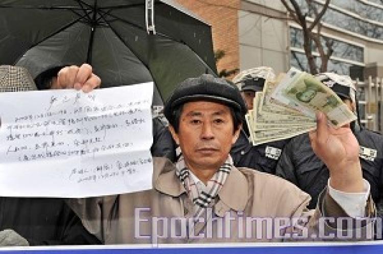 Qihao Jin shows the media the $500 that the CCP authorities gave him to be a secret agent (Zheng Renquan/ The Epoch Times)