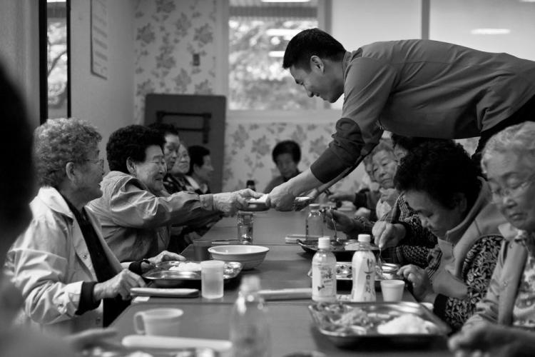 ACT OF SERVICE: A volunteer serves lunch to elderly community housing residents in Pannam. Korean society is aging rapidly, and government policies are struggling to keep up with the pace of change. However, many ordinary Koreans are not prepared to give up on their long tradition of respect and care for the elderly. (Jarrod Hall/The Epoch Times.)