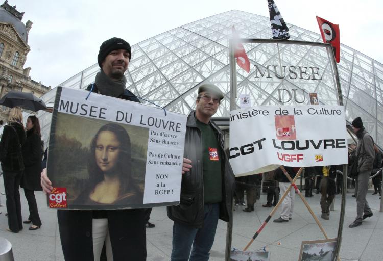 Workers on strike demonstrate with trade union banners to denounce the government measures in front of the Louvre museum Pyramid entrance in Paris on Dec. 3. A strike by Paris museum staff forced the Chateau de Versailles to shut down on Dec. 2. (Francois Guillot/AFP/GETTY IMAGES)