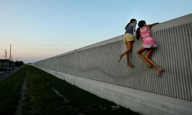 LEAKING: Isabella Lander (L) and Arabella Christiansen climb on the 17th Street Canal levee which broke during Hurricane Katrina. Despite $22 million in repairs, the levee is leaking. Experts fear the levee could fail again in another large storm. (Mario Tama/Getty Images)