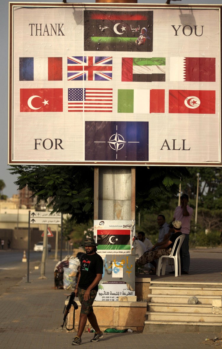 A Libyan rebel walks past a billboard thanking NATO countries for their support in Tripoli on Sept. 1, 2011. (Patrick Baz/AFP/Getty Images)