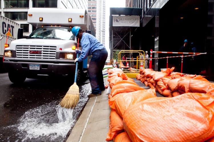 A worker sweeps water on Wall Street in Lower Manhattan, with sandbags behind him. (Amal Chen/The Epoch Times)
