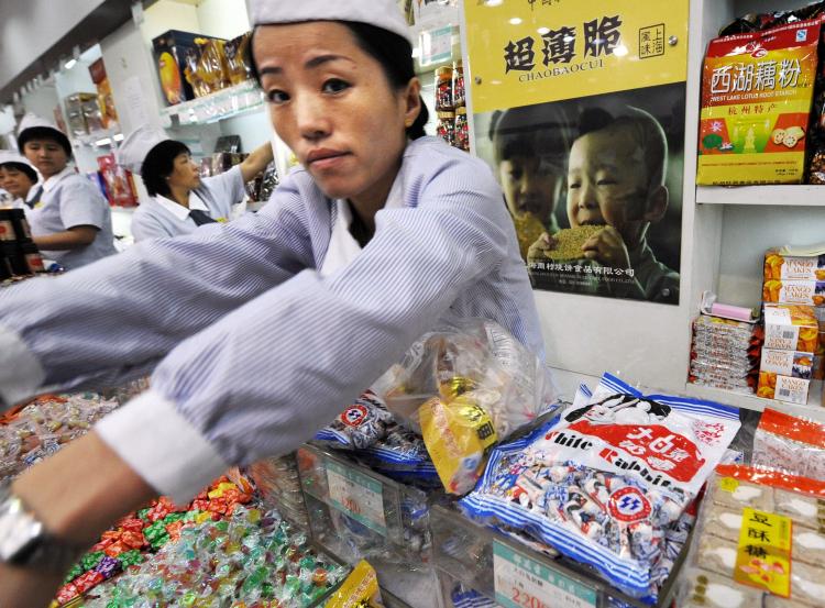 A Chinese shopkeeper serves a customer next to packets of White Rabbit candy on sale at a food store in Shanghai. White Rabbit candy has been found to be contaminated with melamine. (Mark Ralston/AFP/Getty Images)