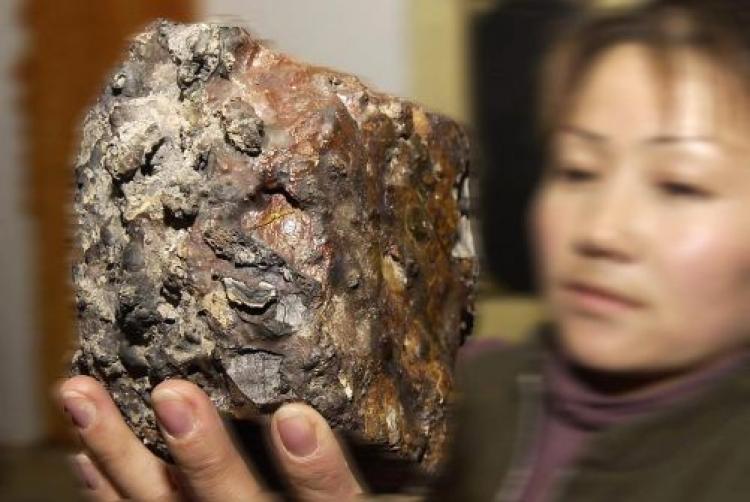 A woman holds up a chunk of meteorite recovered from the hills in China's Gansu province in 2004.