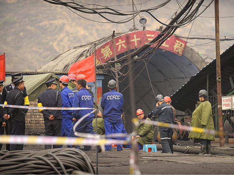 Mine workers and police gather at the entrance to the Wangjialing coal mine where 115 workers were pulled out alive from the flooded mine being built in China's Shanxi province on April 7, 2010. (Peter Parks/AFP/Getty Images)