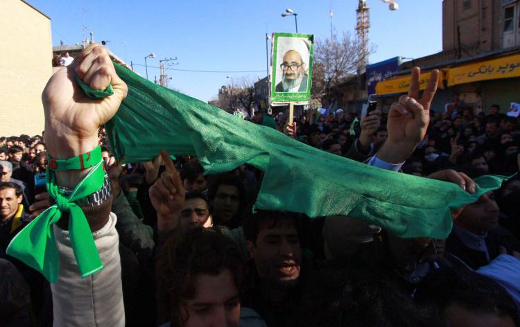 Iranian opposition supporters hold scarfs of their trademark green colour and portraits of Iranian cleric Grand Ayatollah Hossein Ali Montazeri (C) during his funeral procession in the holy city of Qom on December 21, 2009. (-/AFP/Getty Images)