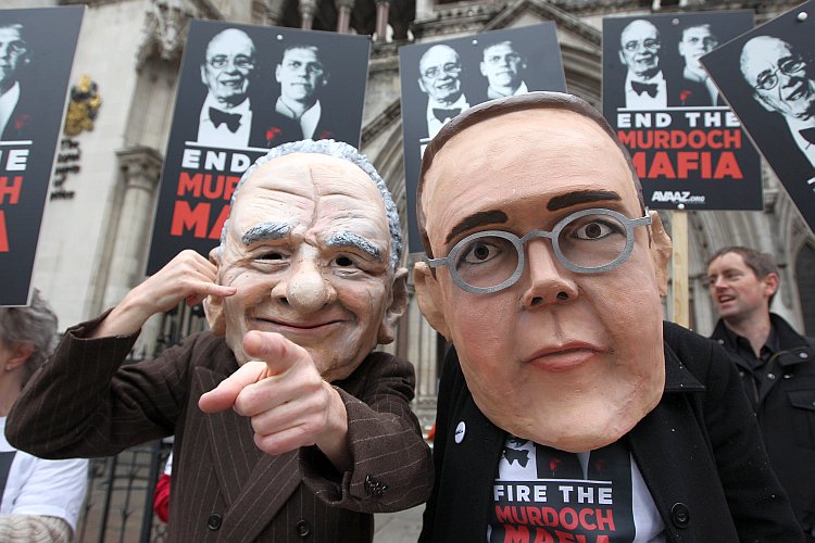Protesters wearing large Rupert and James Murdoch masks