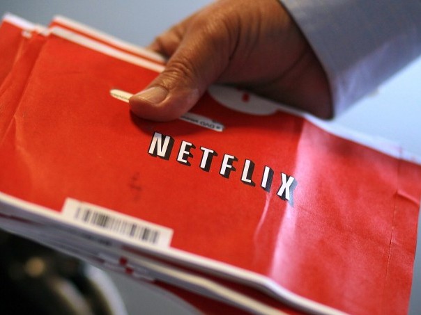 A U.S. Postal worker holds a stack of Netflix envelopes