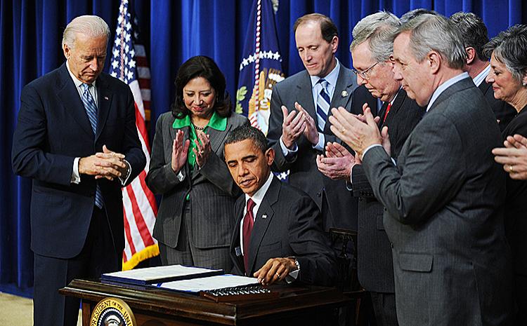 TAX CUTS SIGNED: President Barack Obama, flanked by Vice President Joe Biden and members of Congress, signs the middle-class tax cut bill in the South Court Auditorium on Dec. 17 in Washington. (Olivier Douliery-Pool/Getty Images)