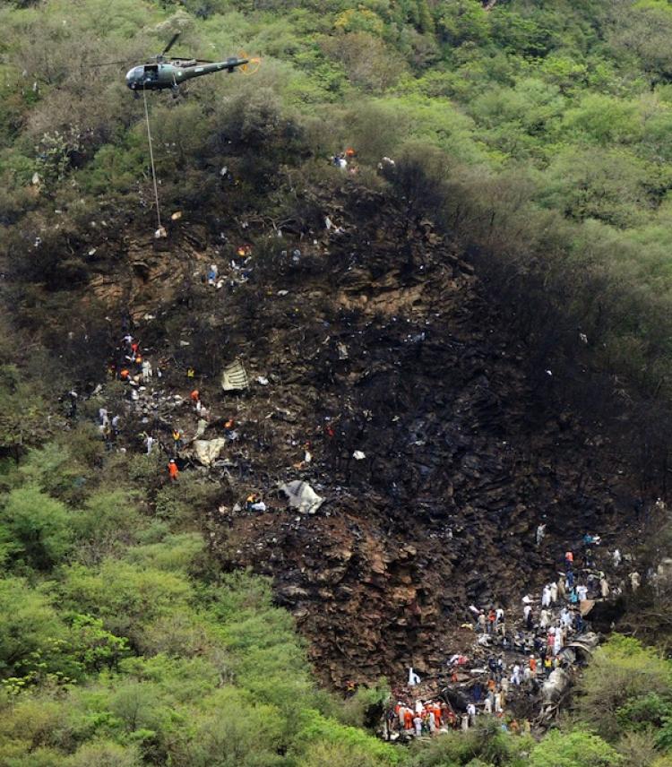 A Pakistani army helicopter carrying remains of plane crash victims takes off from the wreckage-strewn accident site on the outskirts of Islamabad on July 28.  (Amir Qureshi/Getty Images)