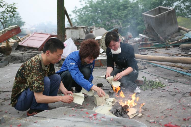 Survivors of the Sichuan earthquake burn paper for their loved ones, a Chinese custom, May 2008. (China Photos/Getty Images)