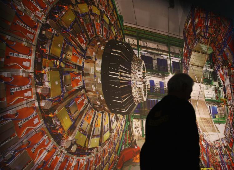 A worker walks past a giant photograph of one part of the Large Hadron Collider, called the 'CMS detector.' (Sean Gallup/Getty Images)