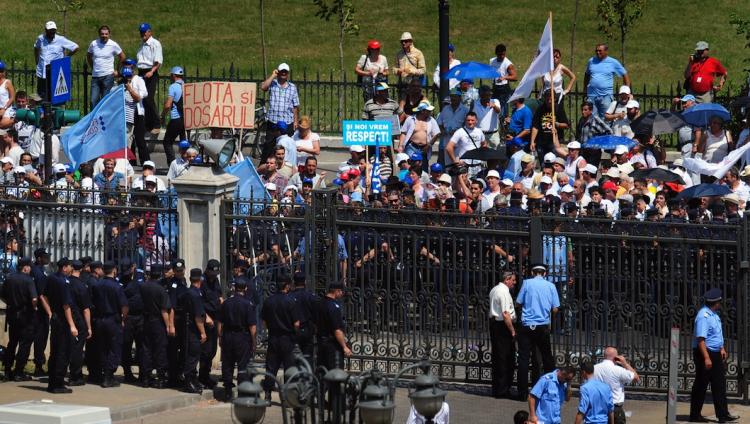 Protesters gather in the front of the Romanian Parliament fence as police take up defensive positions during an anti-government protest in Bucharest on June 15.  (Daniel Mihailescu/Getty Images)