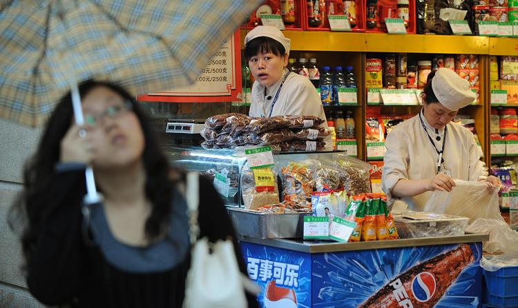 Two Chinese service staff wait for customers at their grocery shop in Shanghai. Food prices have reached a 12-year high that has spurred the government to freeze prices of key consumer items such as grain, edible oil, meat, milk and liquefied petroleum ga (Mark Ralston/AFP/Getty Images)