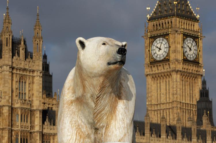 A 16-foot-high sculpture of a polar bear and cub, afloat on a small iceberg, passes in front of the Houses of Parliament on the River Thames in London, January 2009. (Oli Scarff/Getty Images)