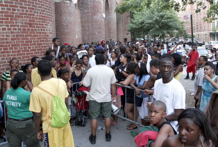 An employee of the Department of Parks and Recreation (center with megaphone) speaking to local residents at the Jackie Robinson Recreation Center in West Harlem on Tuesday. Many locals were denied entry to the pool, and were given different reasons for not being allowed in. (Tim McDevitt/The Epoch Times