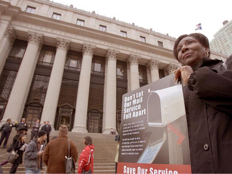 GOING POSTAL: A postal worker protests proposed cuts by the Postal Service outside the Farley Main Post Office on 8th Avenue.  (Edward Dai/The Epoch Times)