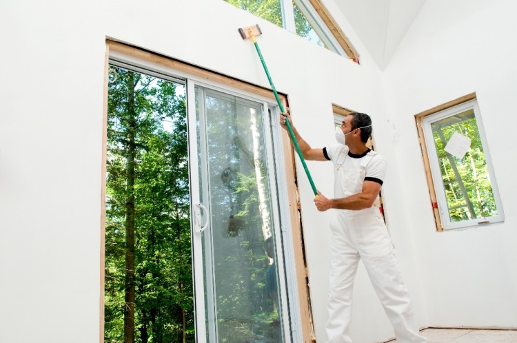 A man sands drywall in an unfinished house, before painting.  photos.com