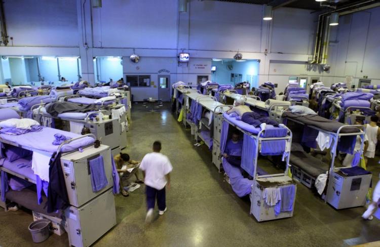 An inmate  at the Mule Creek State Prison walks near his bunk bed in a gymnasium that was modified to house prisoners in Ione, California. (Justin Sullivan/Getty Images)