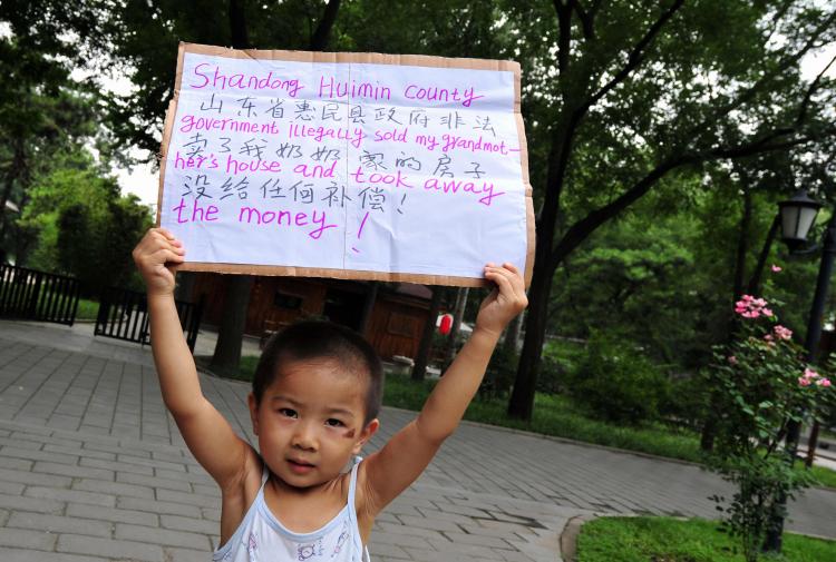 A child displays a placard in a protest park in Beijing which reads 'Shandong Huimin county government illegally sold my grandmother's house and took away the money!' on August 9, 2008. (Frederic J. Brown/AFP/Getty Images)