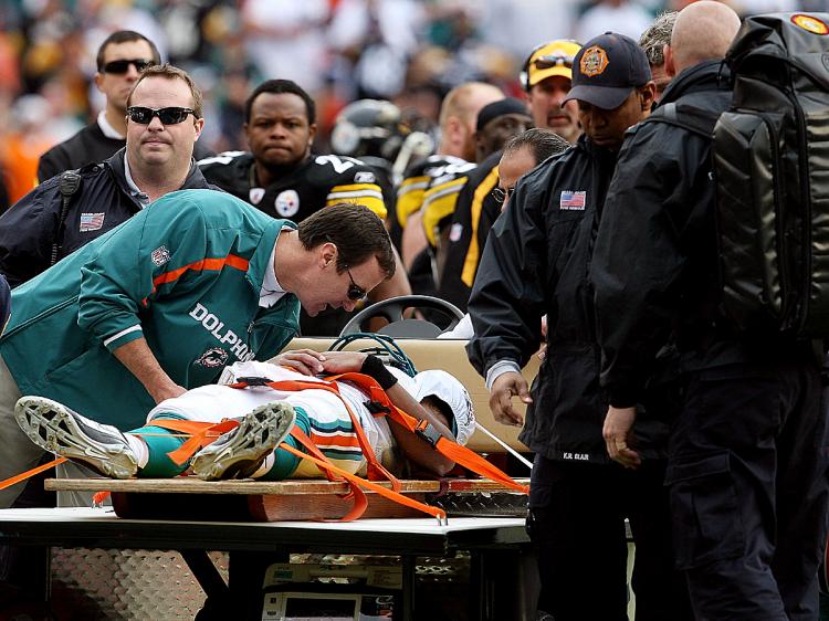 Quarterback Pat White of the Miami Dolphins is carted off the field after being knocked unconscious in the third quarter. (Doug Benc/Getty Images)