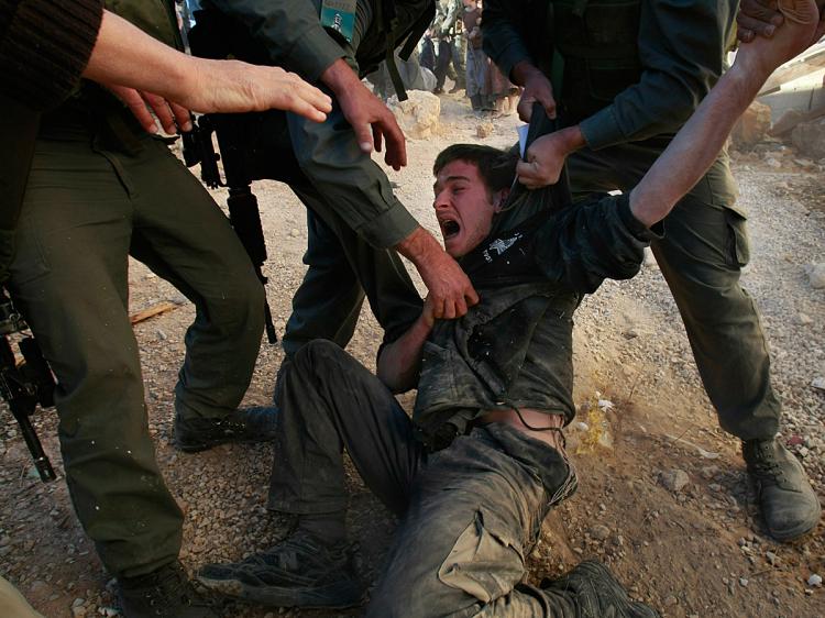 Israeli police struggle to restrain a right-wing Jewish settler as they evacuate Israeli extremists from a disputed house in the West Bank city of Hebron, December 4, 2008.    (David Silverman/Getty Images)