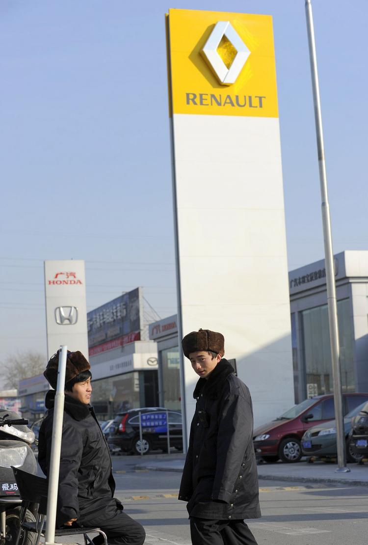 ESPIONAGE: Two security men are on duty next to a sign displaying the logo of French automaker Renault SA at a dealership in Beijing on Jan. 10. Renault has suspended three top managers for allegedly leaking secrets about its electric car program to Chinese agents. (Liu Jin/AFP/Getty Images)