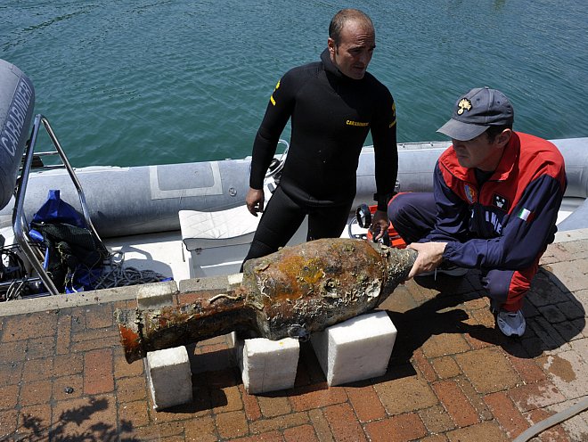 The Carabinieri dive team of Liguria examine a recovered amphora, or storage jar, found at the site of a 2,000-year-old Roman shipwreck off the coast of Italy near Genoa