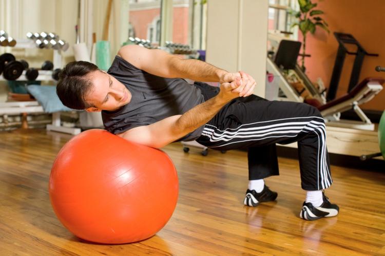 BODY TORQUE: A great exercise for rotational strength. If youâ��ve never done it before, have someone spot the ball. (Henry Chan/Epoch Times Staff, Space courtesy of Fitness Results)