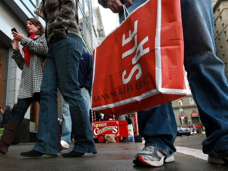 A shopper holds a Banana Republic bag that advertises a sale as he waits for a cab December 22, 2008 in San Francisco, California. (Justin Sullivan/Getty Images)