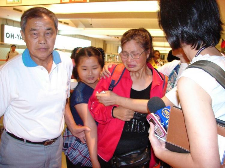 Shao Yuhua (C) bursts into tears as she reunites with her husband (L) after being detained for a week by Chinese authorities. (Daina Lee/The Epoch Times)