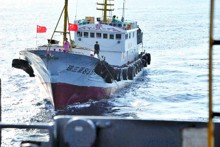 A crewmember on a Chinese trawler uses a grapple hook in an apparent attempt to snag the towed acoustic array of the military Sealift Command ocean surveillance ship USNS Impeccable (Courtesy of U.S. Navy)