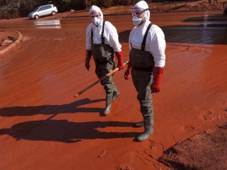 Rescue workers walk on a street covered in red sludge in Devecser, 93 miles west of Budapest on Oct. 11.Toxic sludge from an alumina processing plant in western Hungary burst out of a storage reservoir Oct. 4. Hungarian authorities have arrested the managing director of the company that owned the plant on suspicion of negligence. (Samuel Kubani/AFP/Getty Images)