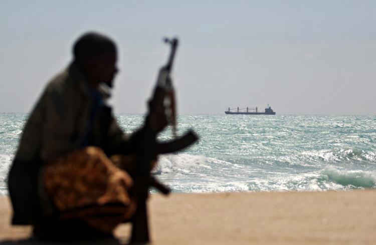 An armed Somali pirate along the coastline while the Greek cargo ship, MV Filitsa, is seen anchored just off the shores of Hobyo town in northeastern Somalia where its being held by pirates.  (Mohamed Dahir/AFP/Getty Images)