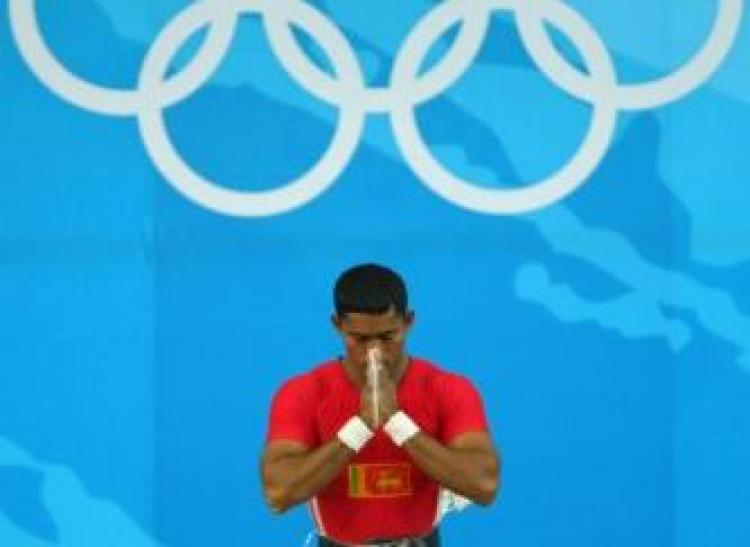 Chinthana Vidanage of Sri Lanka prays during competition in the Men's 62kg group B weightlifting event on Day 3 of the Beijing Olympics. Some athletes are dissatisfied with the service provided by the religious center in the Olympic Village. (Stu Forster/Getty Images)