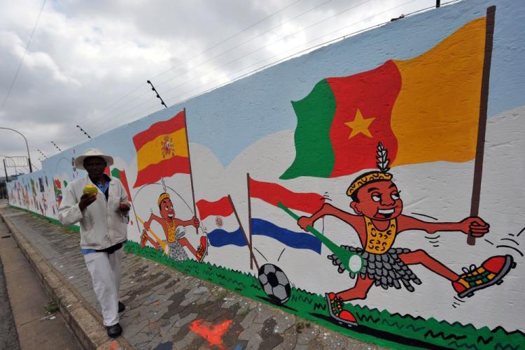 A man walks past a wall painted with flags in Soweto, April 11, of countries taking part in the FIFA World Cup to be held in South Africa from June 11 to July 11. (Alexander Joe/AFP/Getty Images)