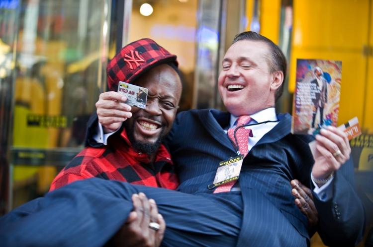 WYCLEF LOVE: Hip-hop artist Wyclef Jean holds Western Union Exec. Stewart A. Stockdale at a promotion for the company's new gift card in Times Square. (Aloysio Santos/The Epoch Times)