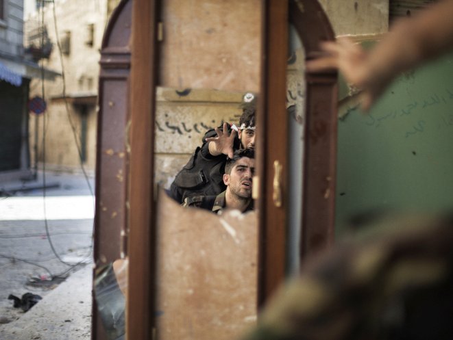 Free Syria Army fighters are reflected in a mirror they use to see a Syrian Army post only 50 meters away as they man a position in the Old City of Aleppo September 16, 2012. The UN announced Monday that there is an alarming presence of foreign forces in Syria.