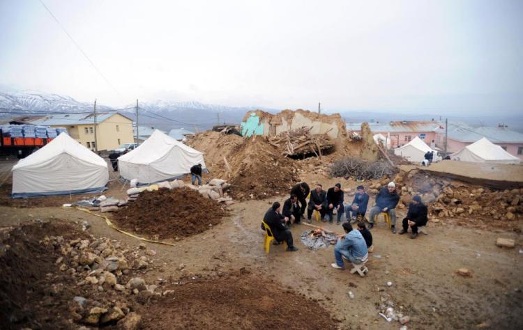 Villagers gather around a camp fire amongst tents and debris of what used to be houses in the village of Okcular on Monday.  (AFP/Getty Images)