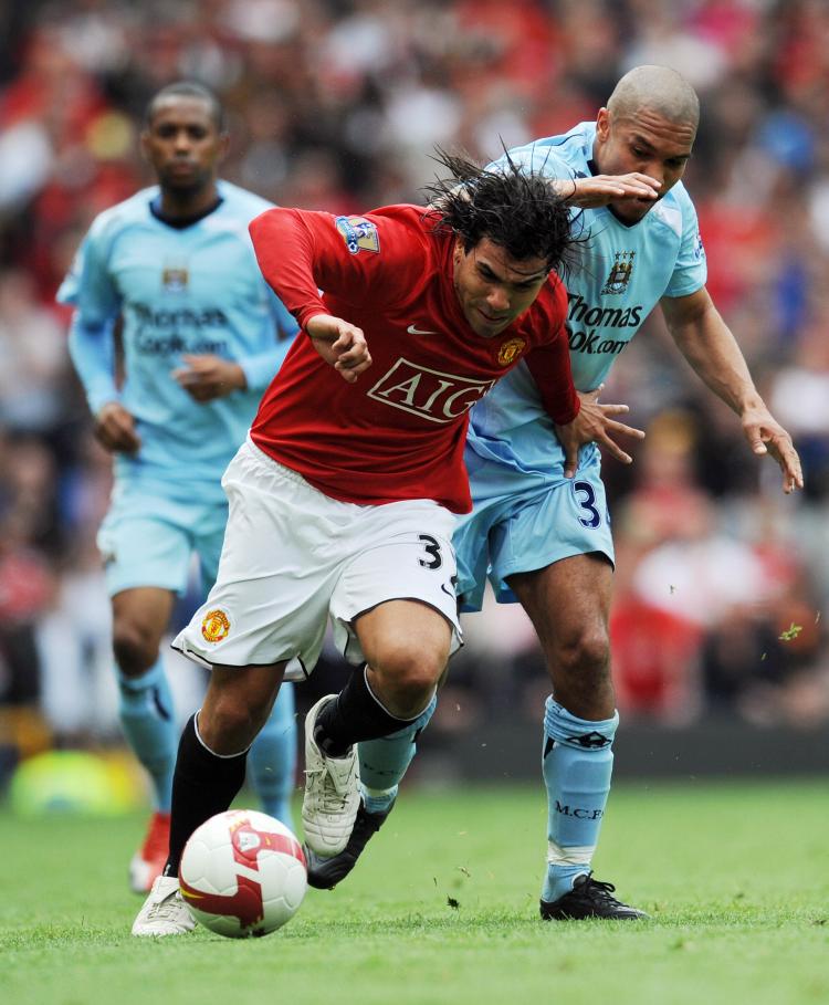 CHANCE TO SHINE: Carlos Tevez (front) fends off a Manchester City defender in another strong performance for United. (PAUL ELLIS/AFP/Getty Images)